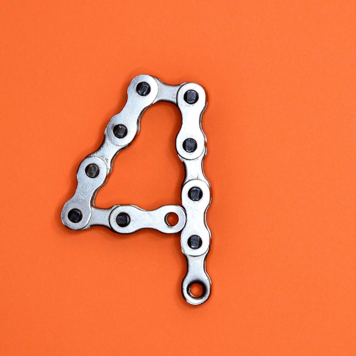 A creative design of the number four formed with a metal chain against an orange background, offering ample copy space.